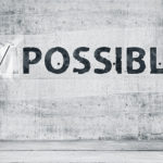 Man turning the word “Impossible” into “Possible”